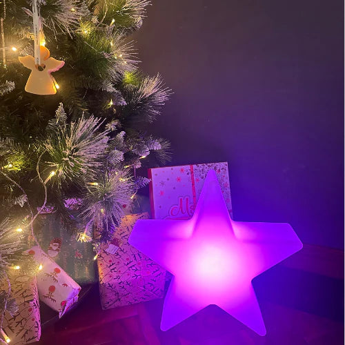 LED RGB Colour-Changing Star Light – lit purple beside a Christmas tree