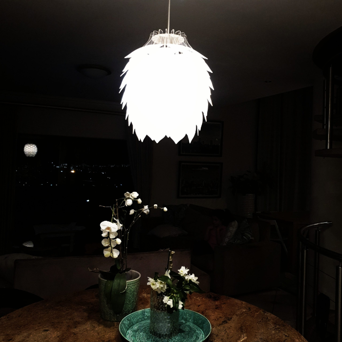 Honey Badger Pinopoly Pendant Light – lit frosted white pendant above a dining table at night