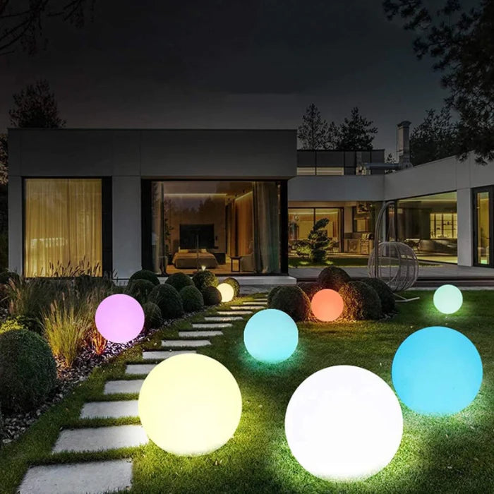 LED RGB Colour-Changing Ball Light – lit balls in different colours on a garden lawn at night