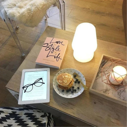 RGB Colour-Changing LED Table Lamp with Remote – lit lamp on a coffee table with a book and tablet