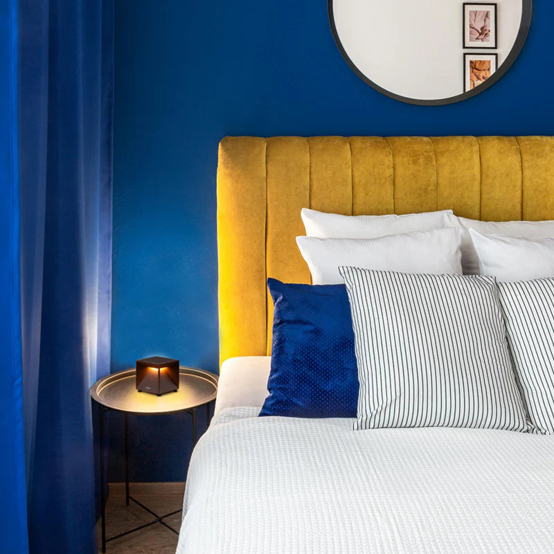 SPAZIO Cubox Mini Rechargeable Dimmable Table Lamp – lit on a bedside table in a blue bedroom