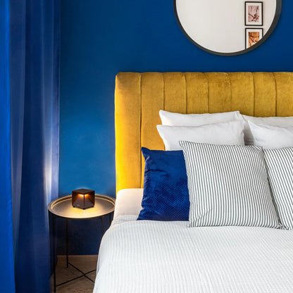 SPAZIO Cubox Mini Rechargeable Dimmable Table Lamp – lit on a bedside table in a blue bedroom