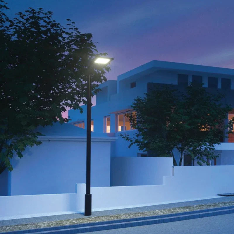SPAZIO Sunstreet Solar LED Street Light – lit on a pole beside a house at dusk