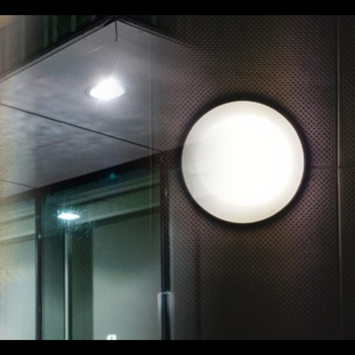 Synerji Round LED Bulkhead – lit on a dark wall at night